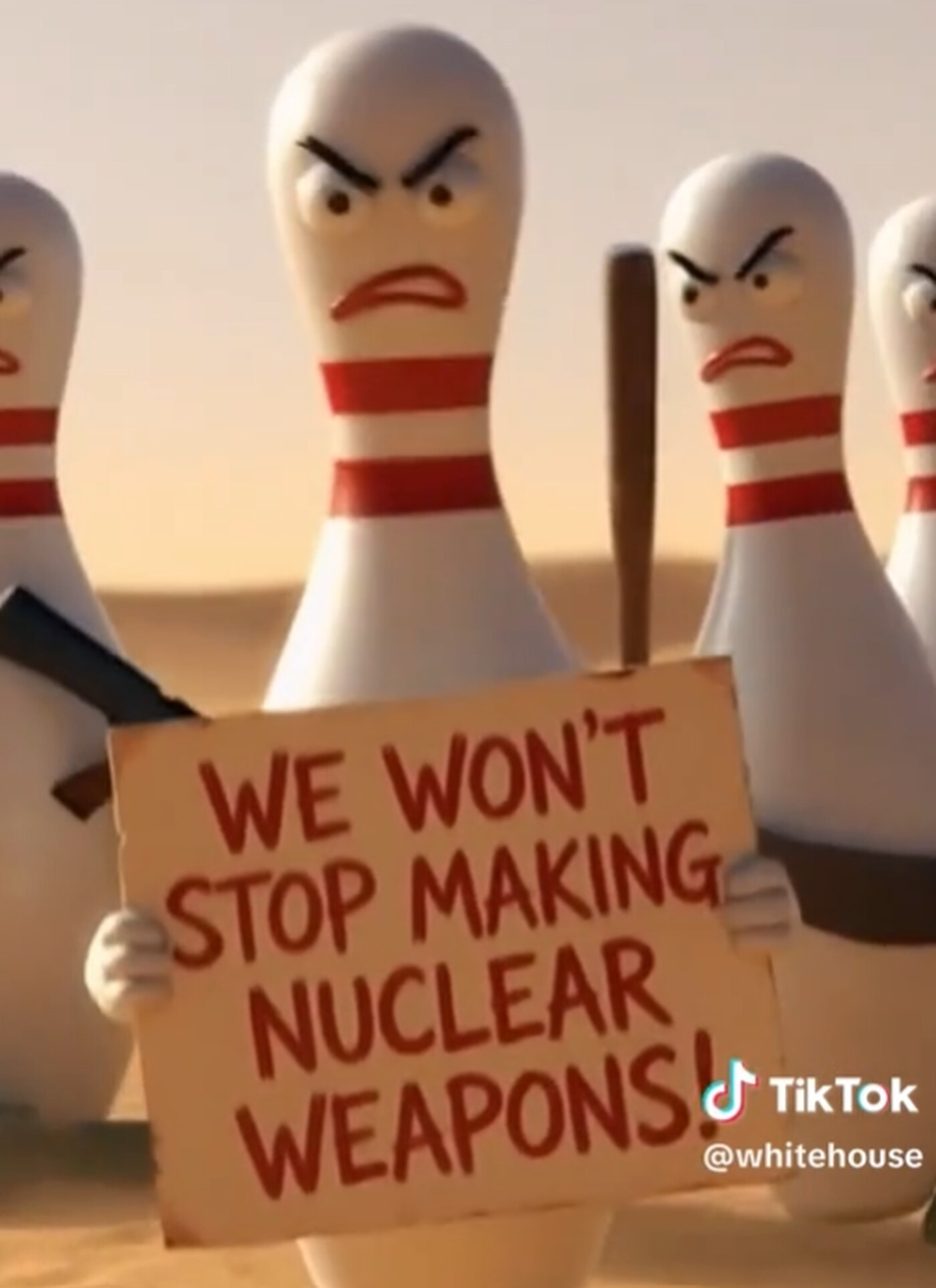 bowling pins with machine guns on their backs. They are looking angry and holding up a sign that says: "We won't stop making nuclear weapons!"